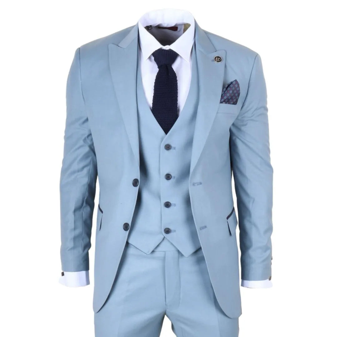 Traje azul claro con camisa blanca, corbata oscura y pañuelo de bolsillo sobre fondo blanco.