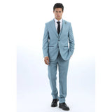 Hombre con traje azul claro, camisa blanca y corbata negra sobre fondo blanco.