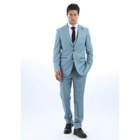 Hombre con traje azul claro, camisa blanca y corbata negra sobre fondo blanco.