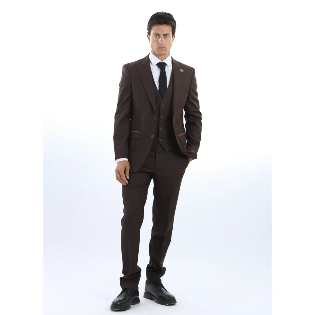 Hombre con traje marrón, camisa blanca y corbata negra sobre fondo blanco.