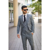 Hombre con traje gris y gafas de sol en una calle de la ciudad.