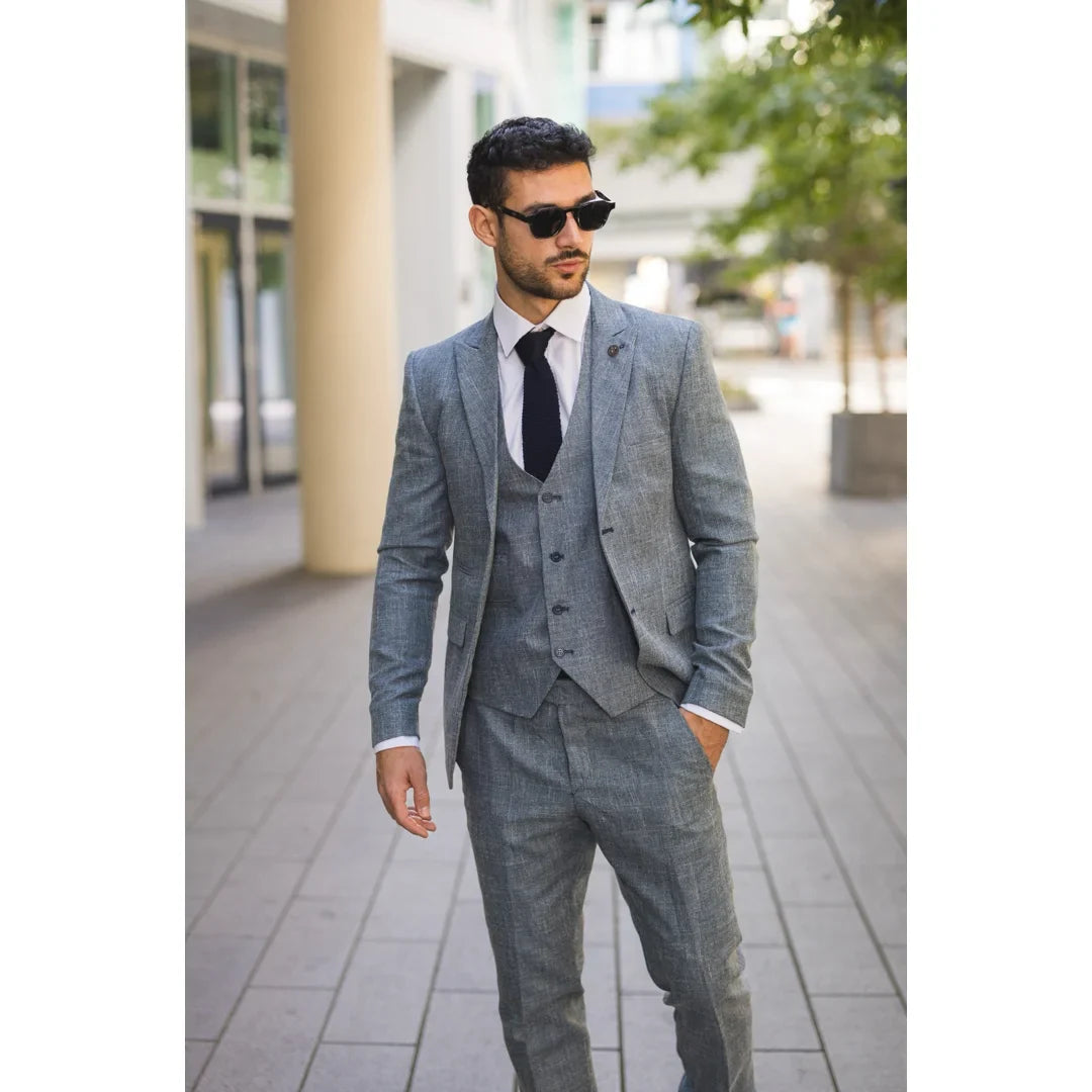 Hombre con traje gris y gafas de sol en una calle de la ciudad.