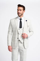 Hombre con traje a cuadros gris claro, camisa blanca y corbata negra sobre fondo blanco.