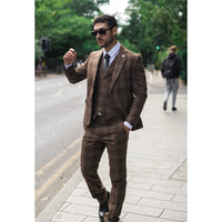 Hombre con traje marrón caminando por una calle de la ciudad.