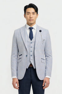 Hombre con chaqueta gris claro, chaleco azul marino y corbata azul oscuro sobre fondo blanco.