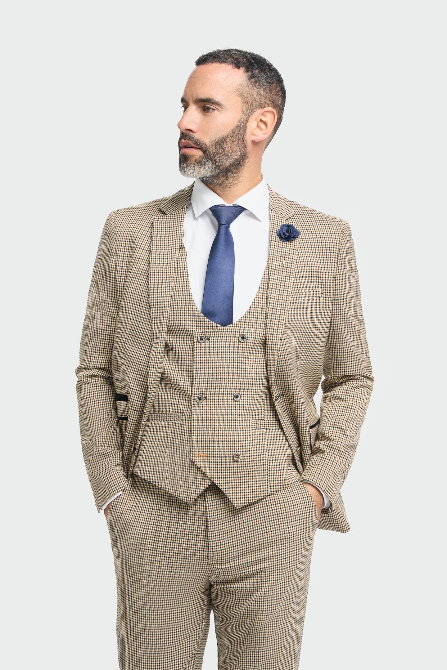 Hombre con traje a cuadros beige y corbata azul sobre fondo blanco