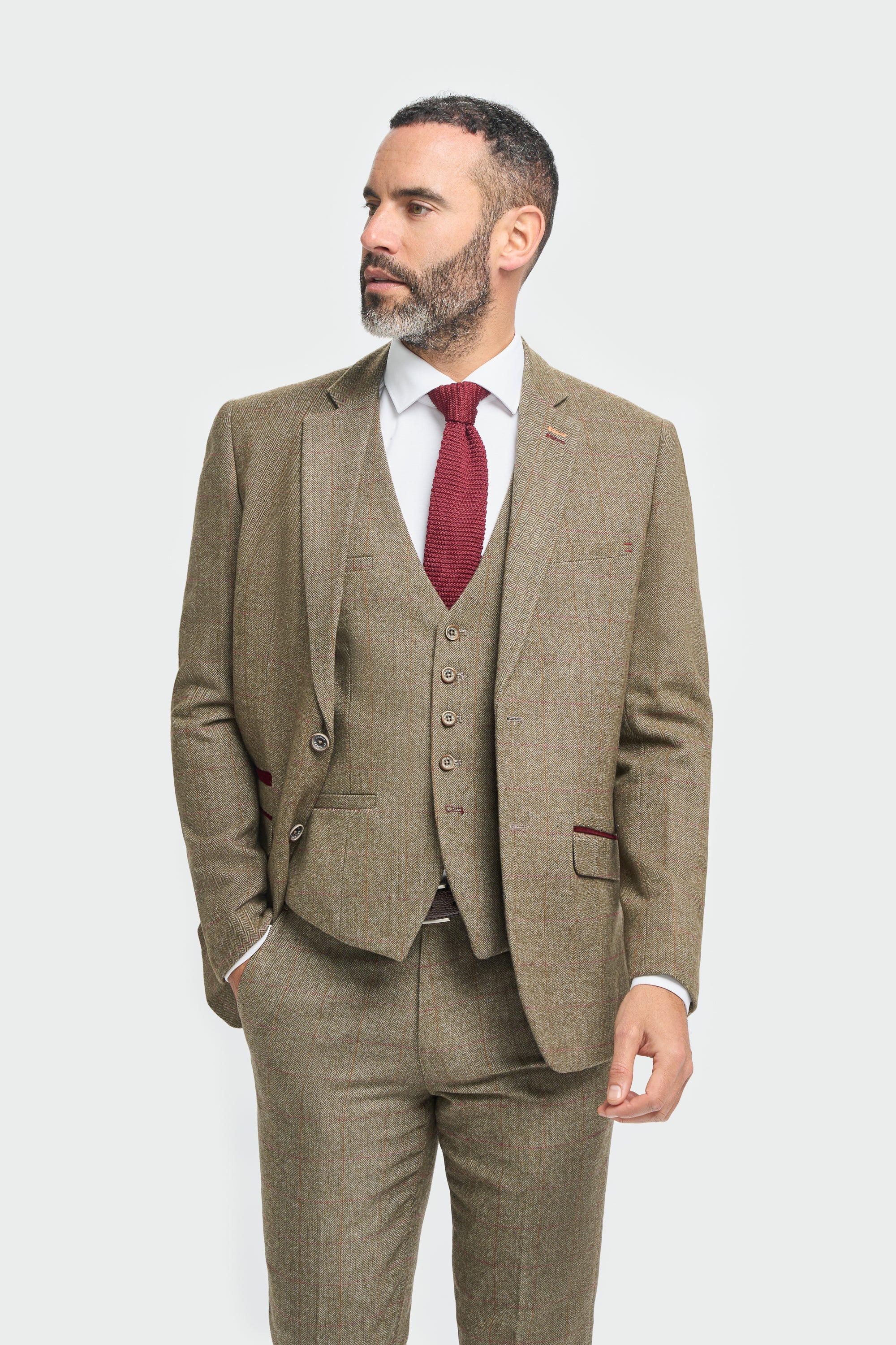 Hombre con traje marrón y corbata roja sobre fondo blanco