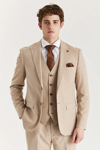 Hombre con traje beige y corbata marrón sobre fondo blanco