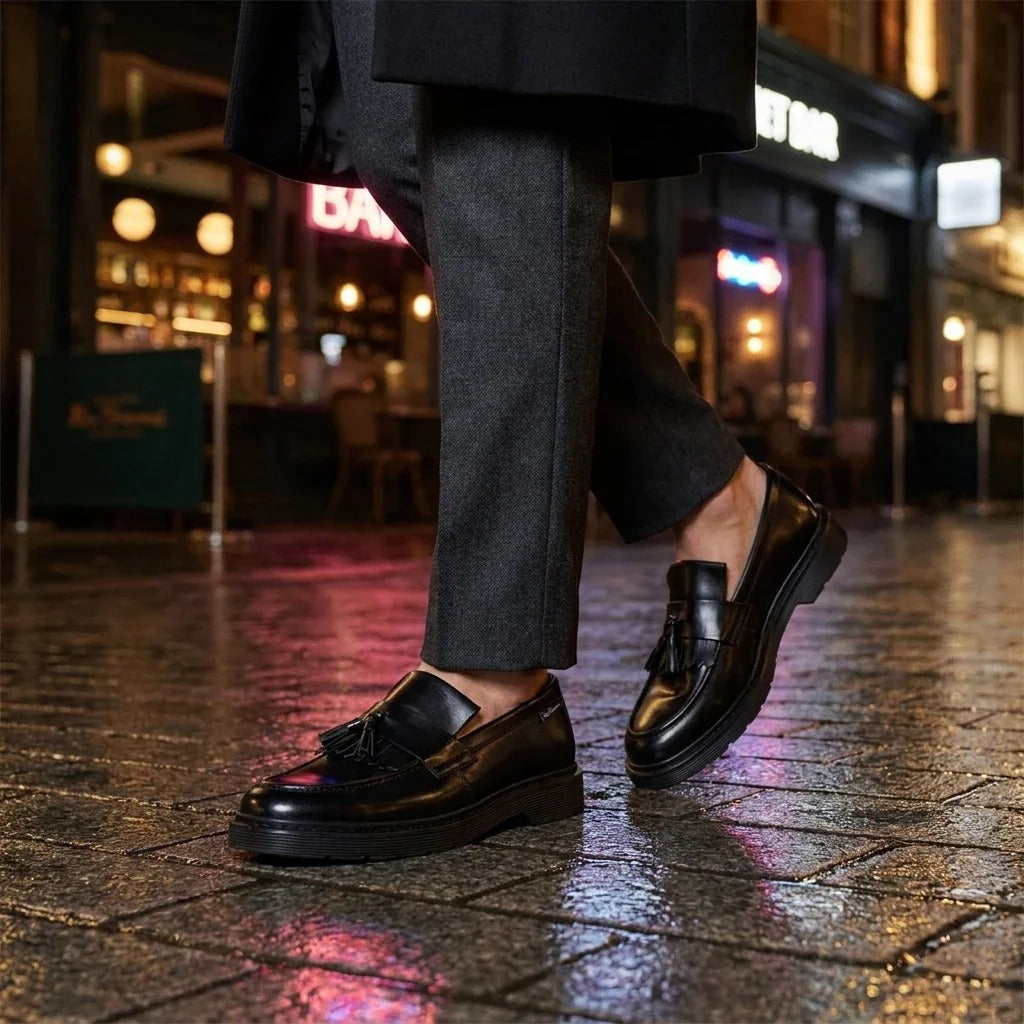 Zapatos mocasines de hombre de cuero negro con suela gruesa y borlas.