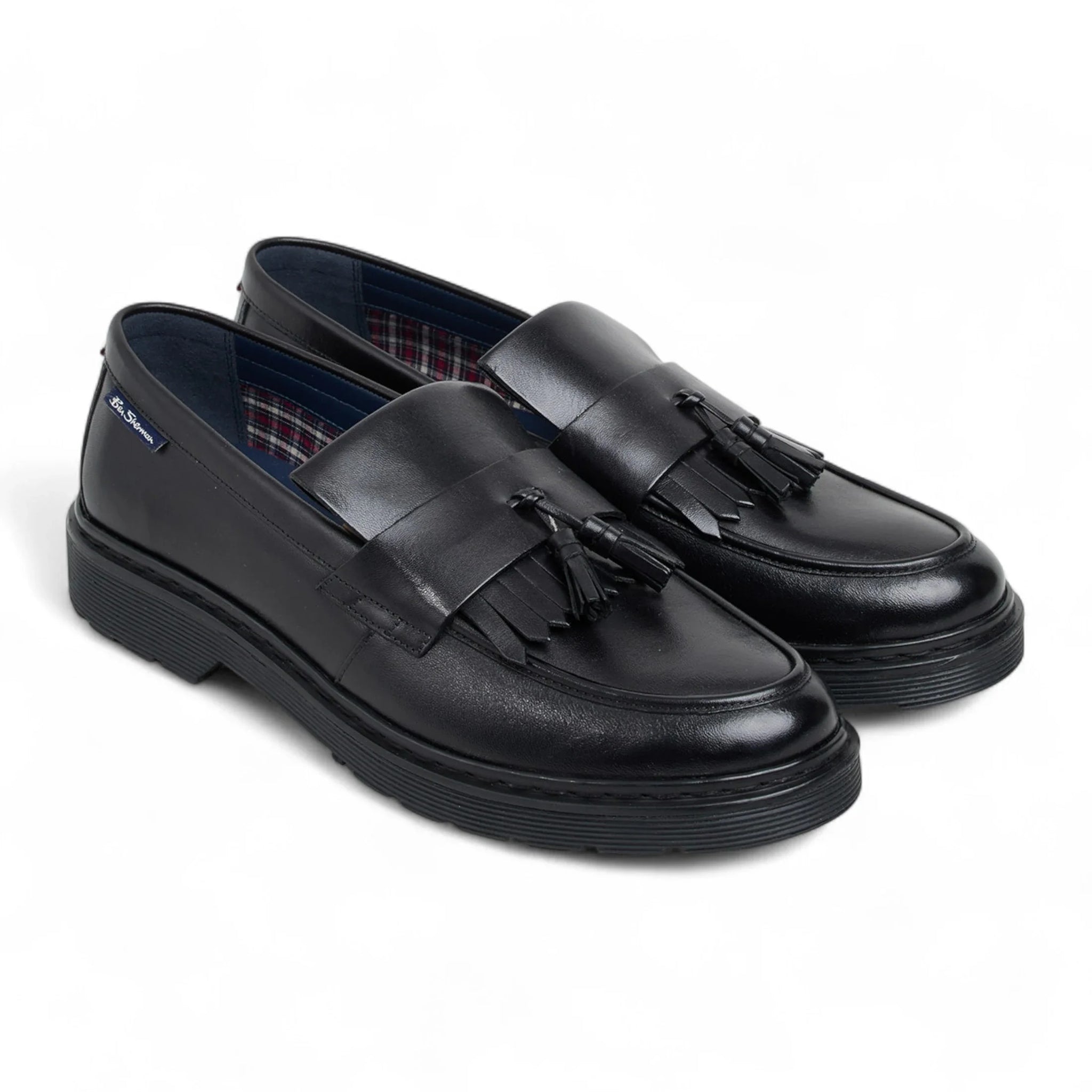 Zapatos mocasines de hombre de cuero negro con suela gruesa y borlas.