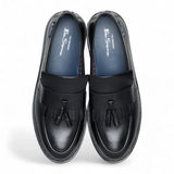 Zapatos mocasines de hombre de cuero negro con suela gruesa y borlas.