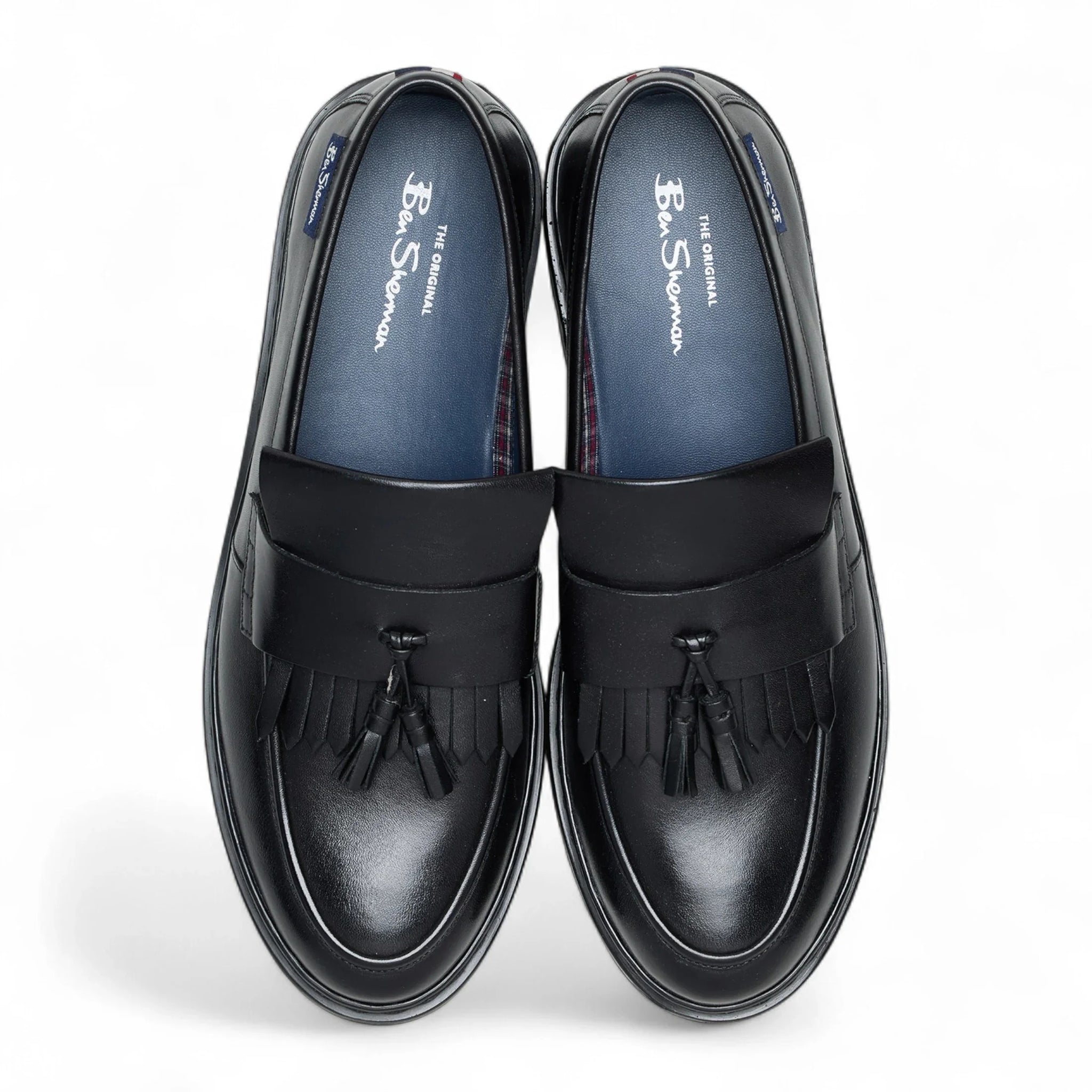 Zapatos mocasines de hombre de cuero negro con suela gruesa y borlas.