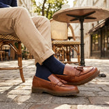 Zapatos mocasines de hombre de cuero marrón claro con suela gruesa y borlas.