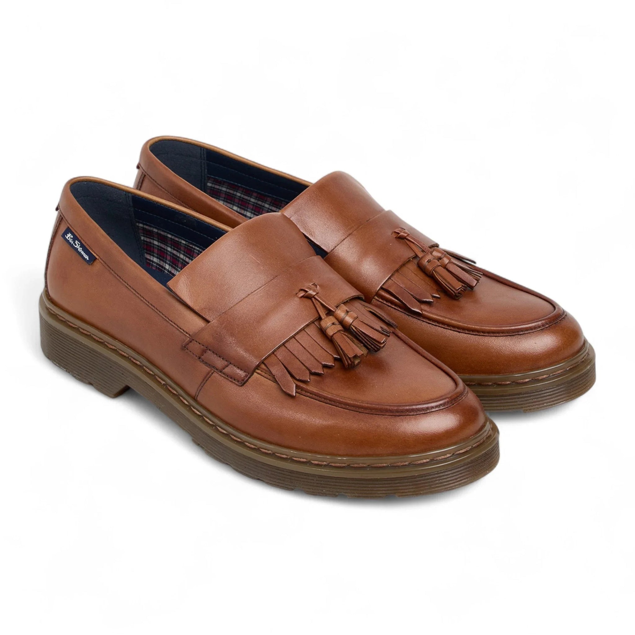 Zapatos mocasines de hombre de cuero marrón claro con suela gruesa y borlas.