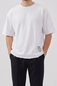 Camiseta blanca de hombre de corte relajado con borde sin rematar, mezcla de algodón y cuello redondo.