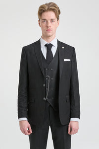 Hombre con traje negro de raya diplomática, camisa blanca y corbata negra sobre un fondo gris claro.